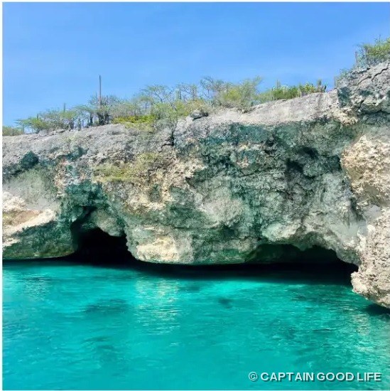 Cave opening in the cliffs above turquoise water