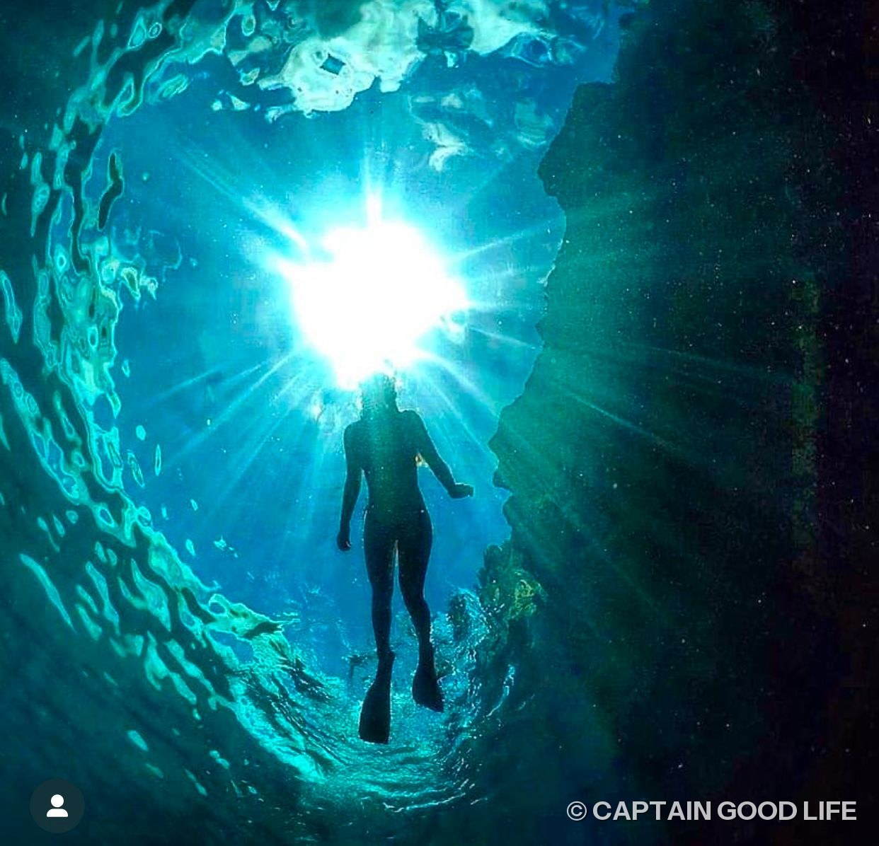Diver silhouetted against the bright opening of the cave